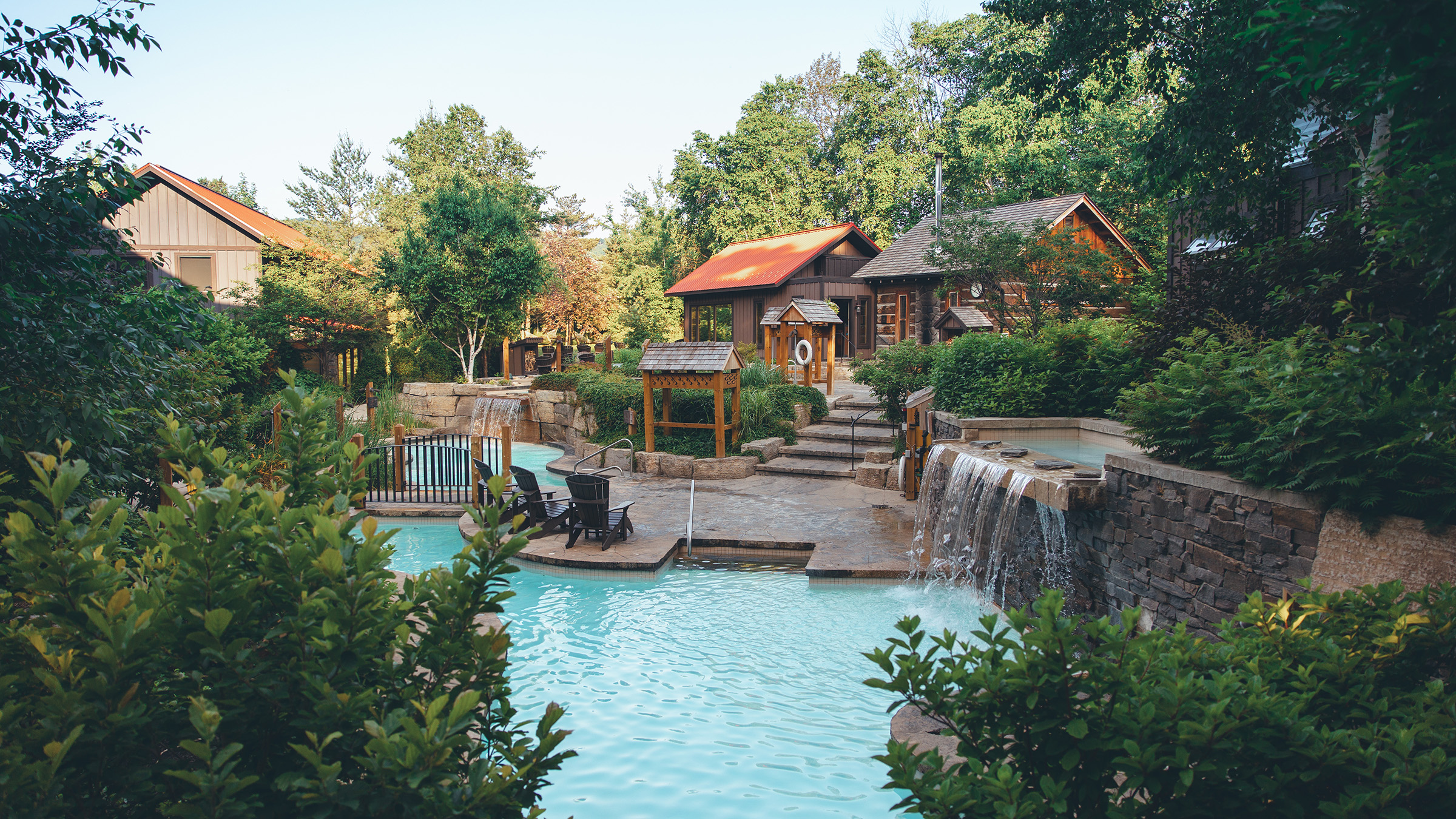 a pool with a waterfall and a house in the background