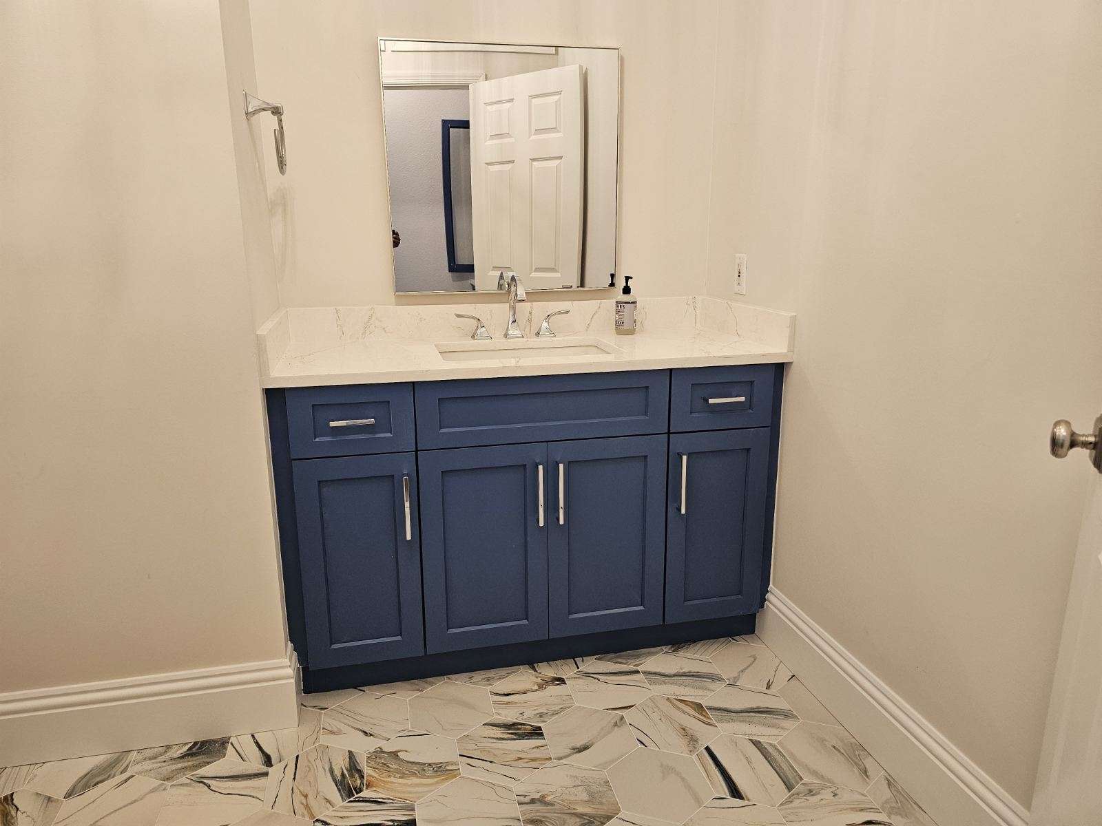 a bathroom with blue cabinets and a mirror