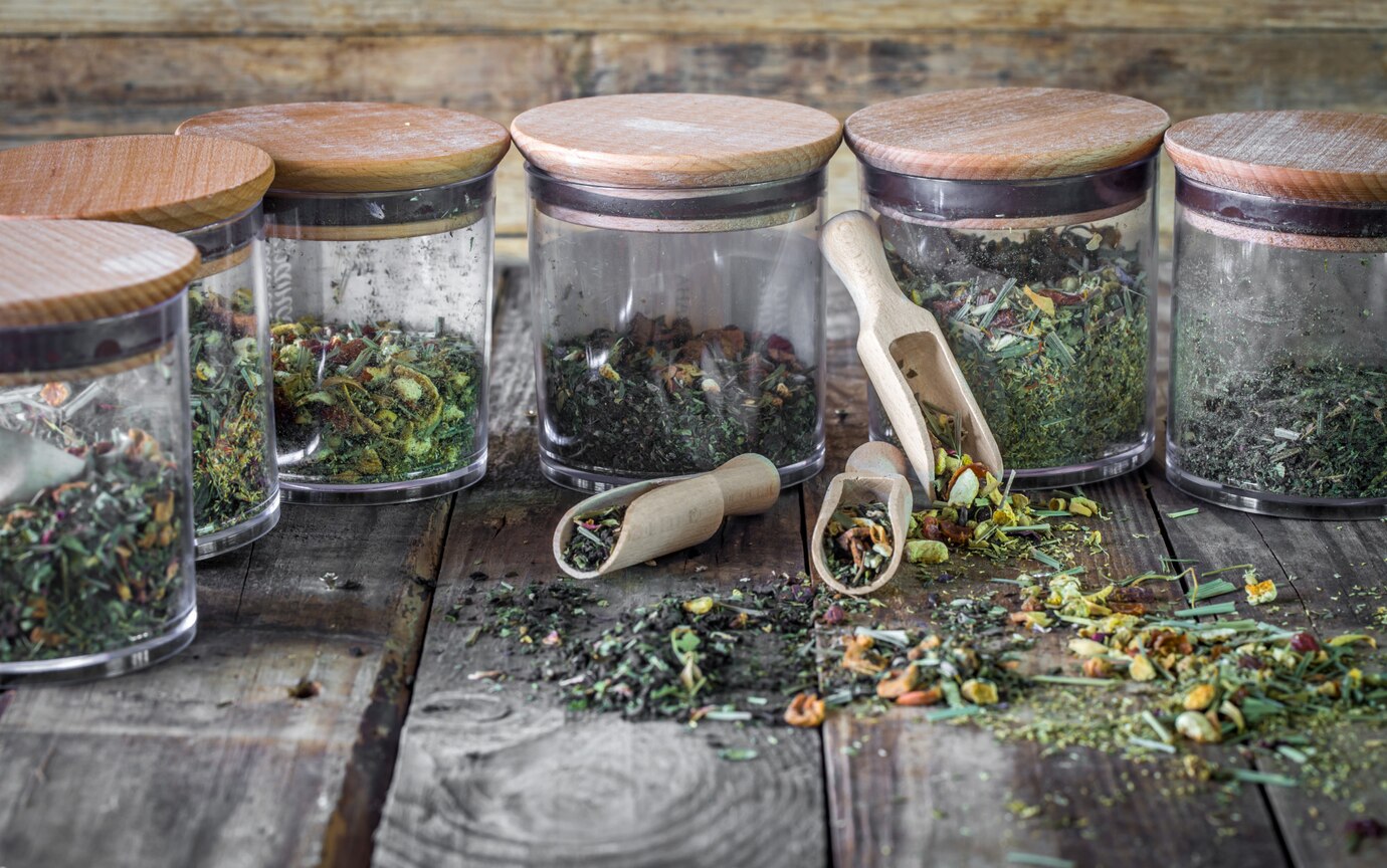 a group of glass containers with different herbs and spices