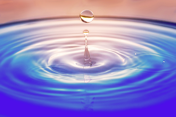 a water droplet falling into a blue surface