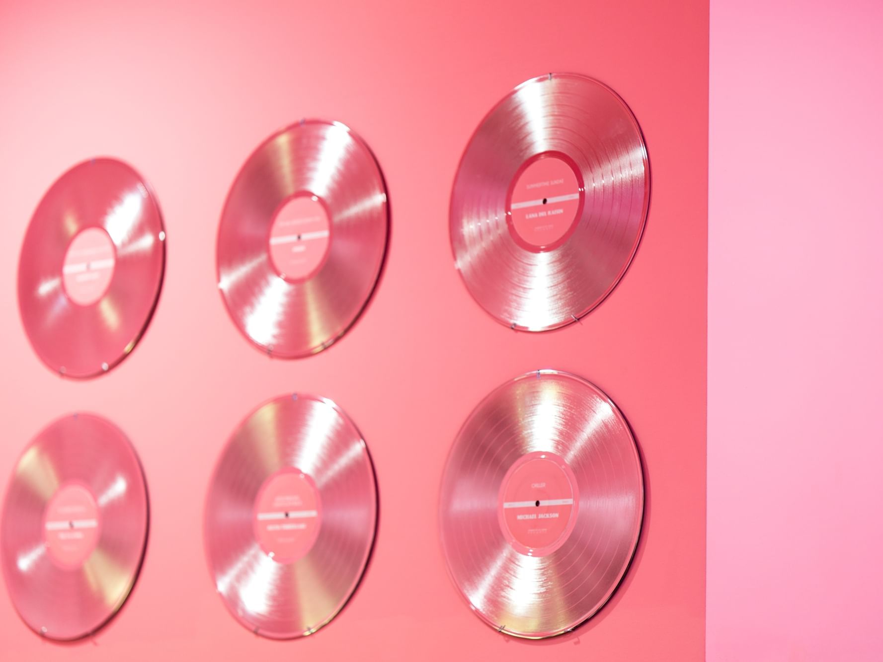 a group of silver records on a pink wall