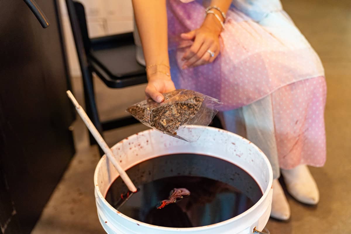 a person pouring a bag of tea into a bucket of liquid