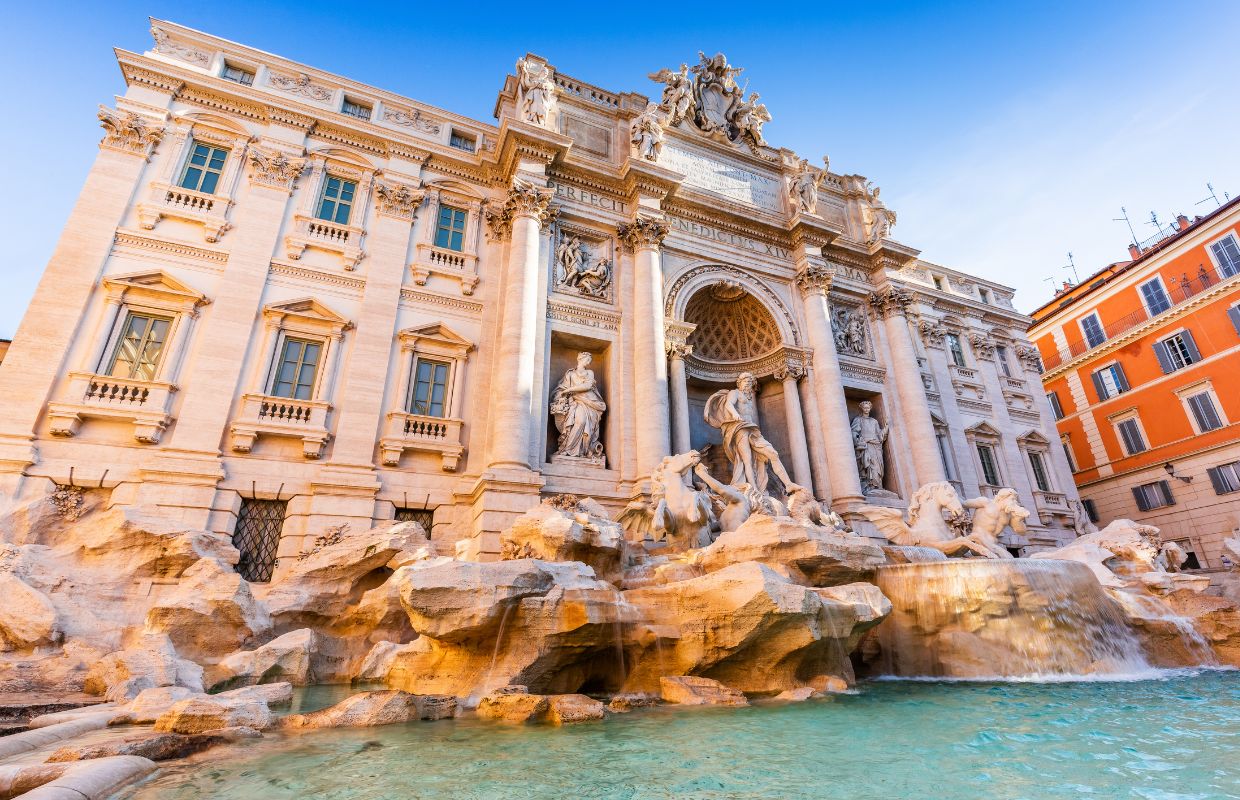 a large stone building with a fountain with Trevi Fountain in the background