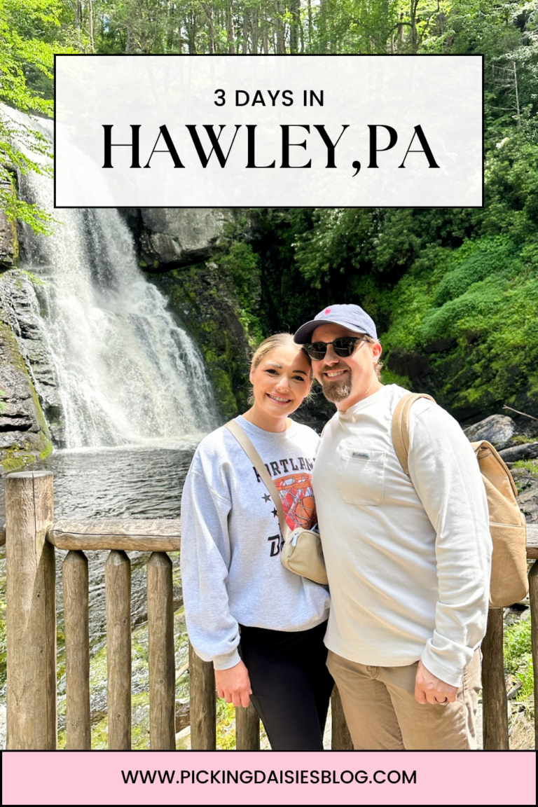 a man and woman posing for a picture in front of a waterfall