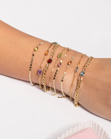 a person's arm with many gold bracelets