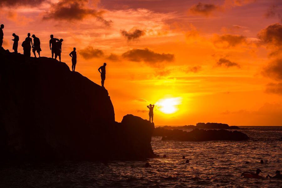 a group of people standing on a rock by the water