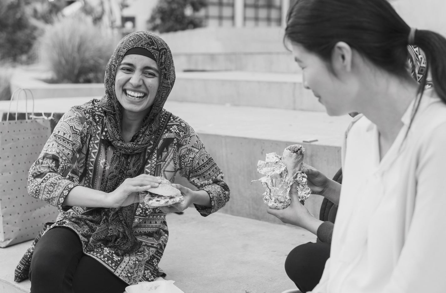 a woman smiling while holding a sandwich