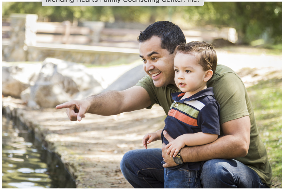 a man holding a child pointing to a small pond