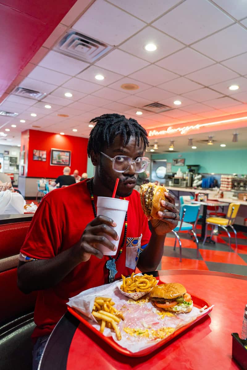 a man eating a burger and drinking a drink