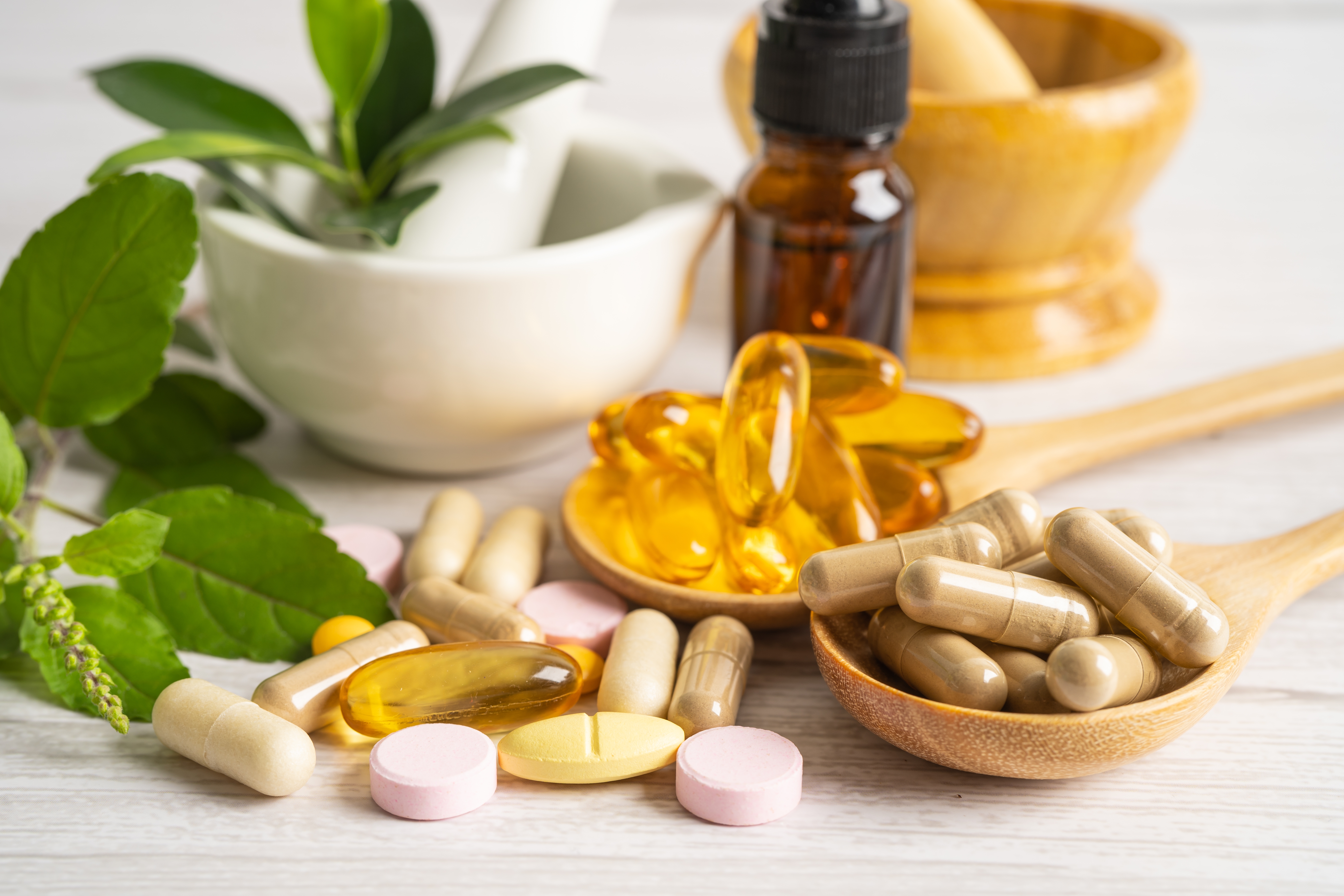 a group of pills in a spoon next to a mortar and pestle