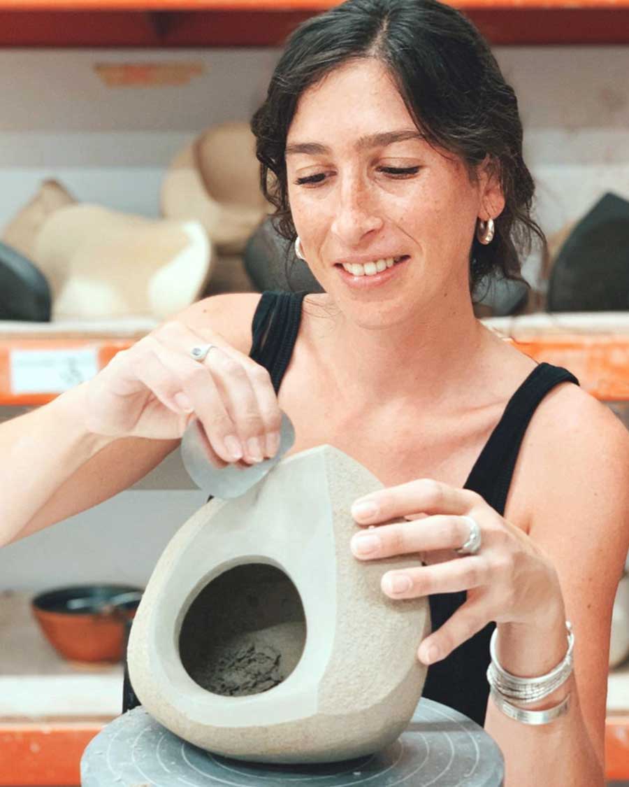 a woman using a sanding tool to sand a sculpture