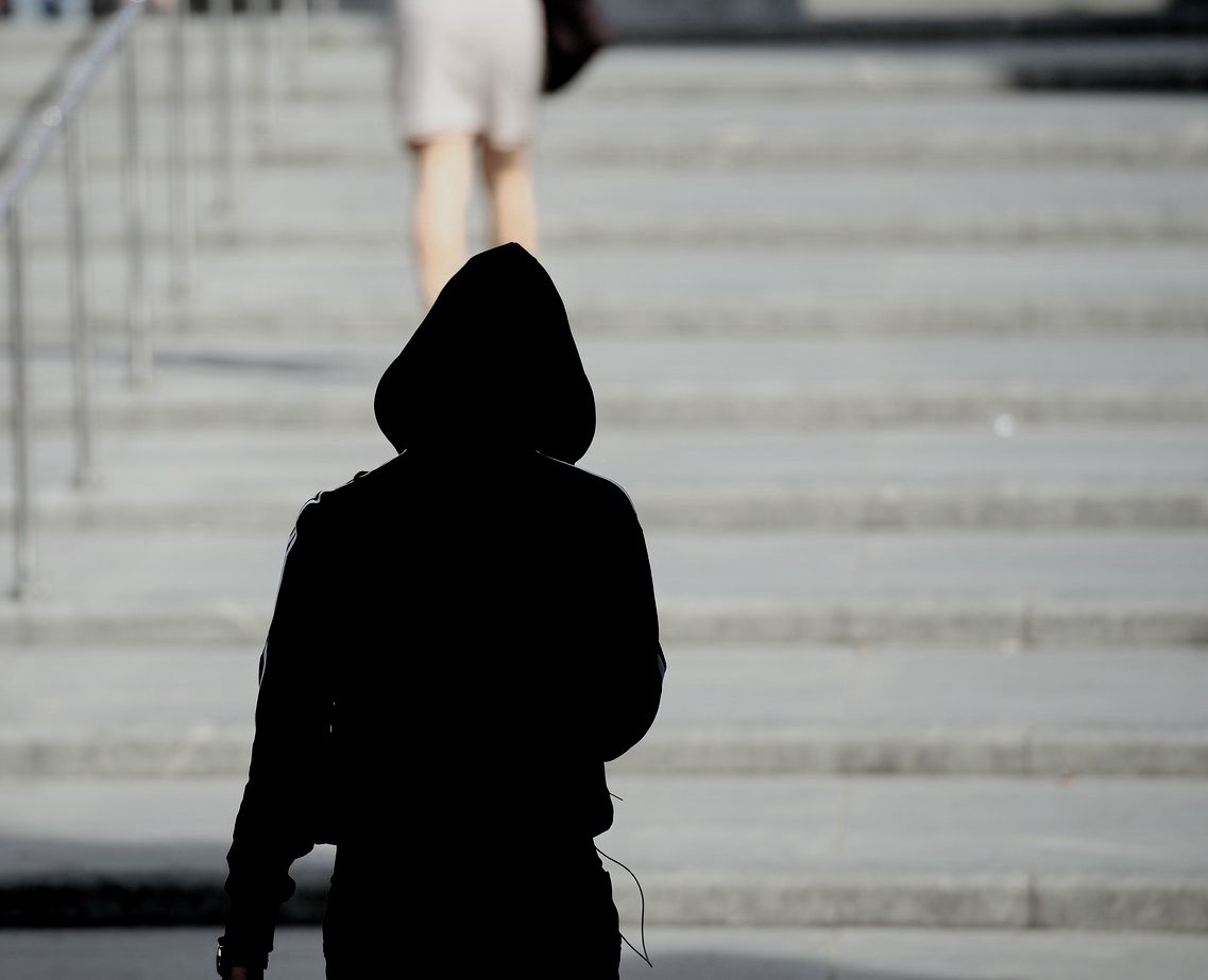 a person in a hoodie walking up stairs