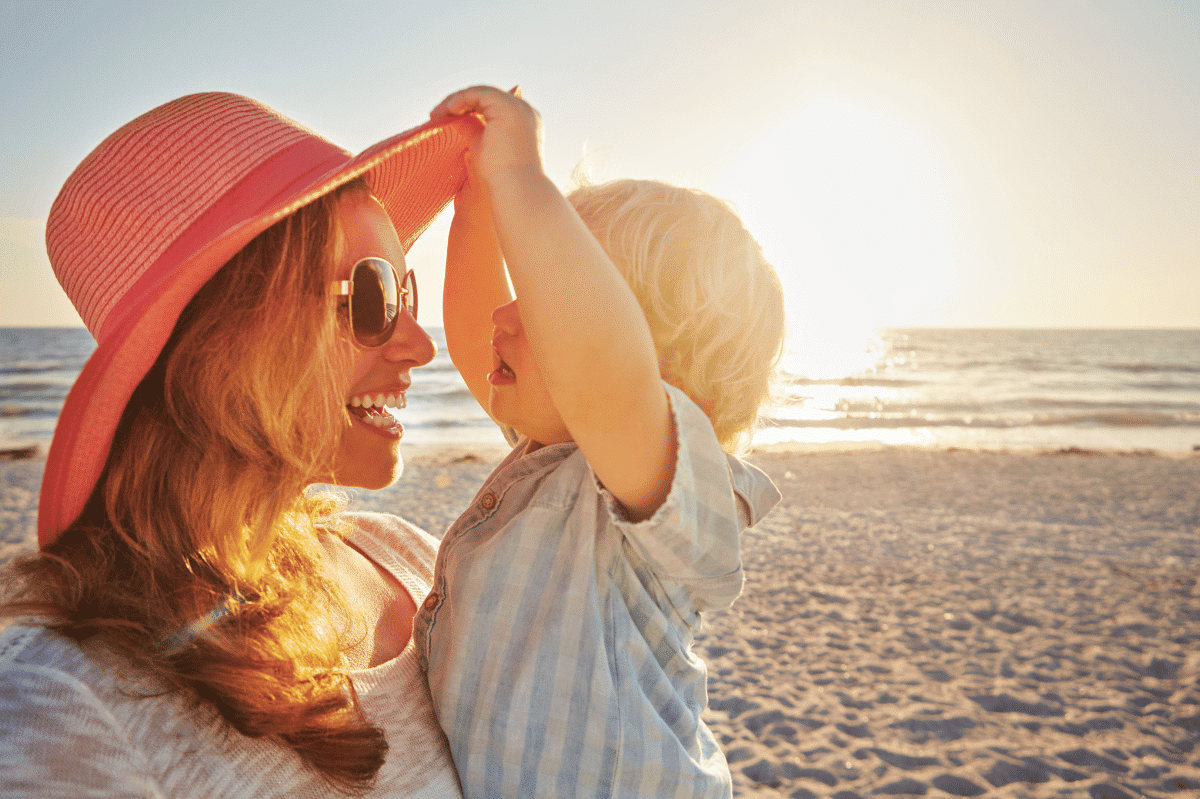 a woman holding a baby on a beach