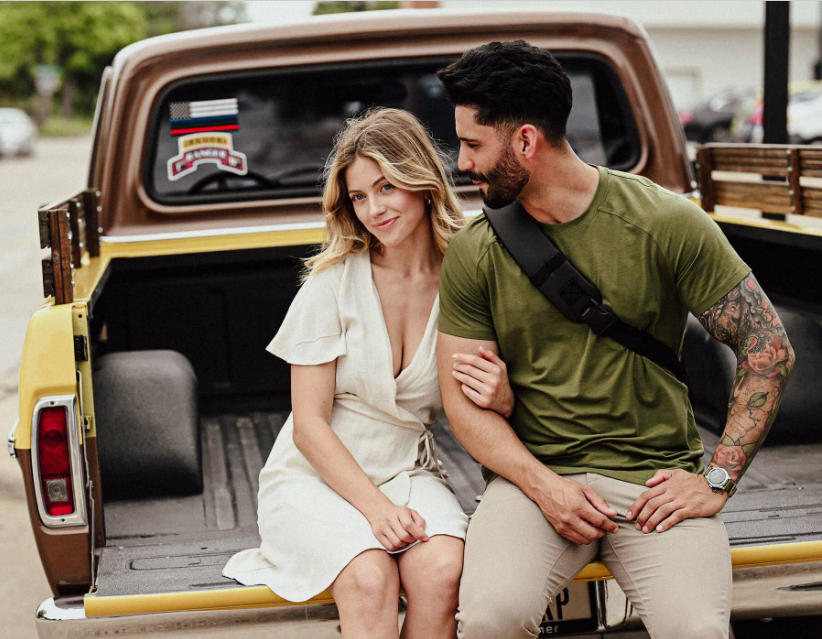 a man and woman sitting on the back of a pickup truck