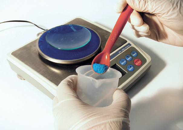 a person holding a measuring cup with a blue powder