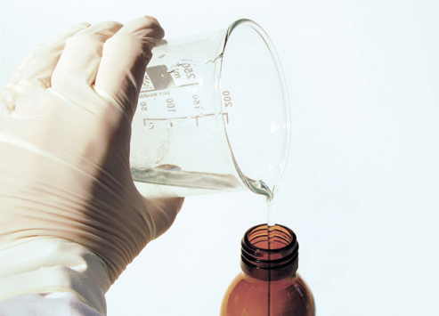 a hand pouring liquid into a bottle