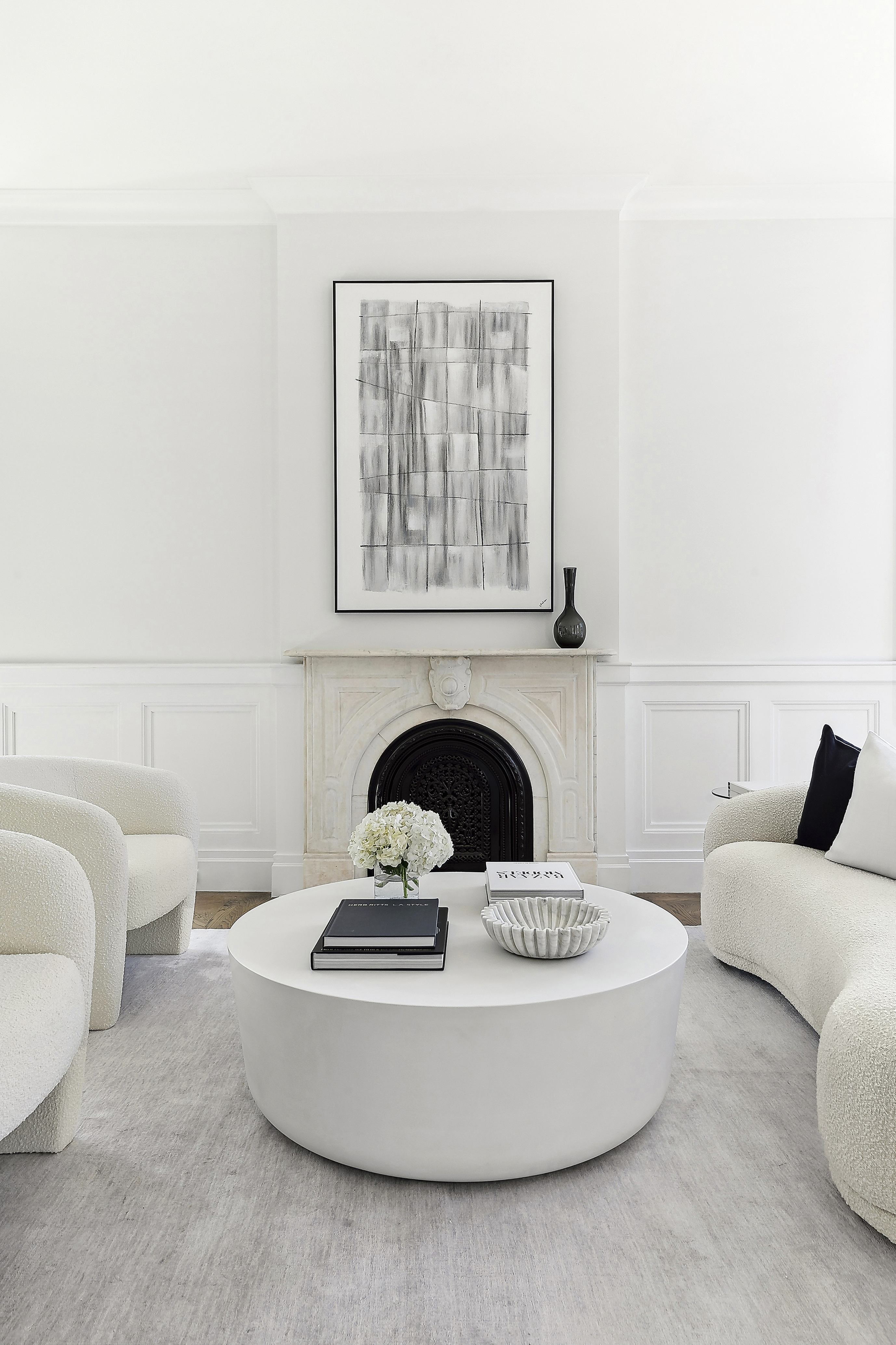 a white living room with a fireplace and a round coffee table