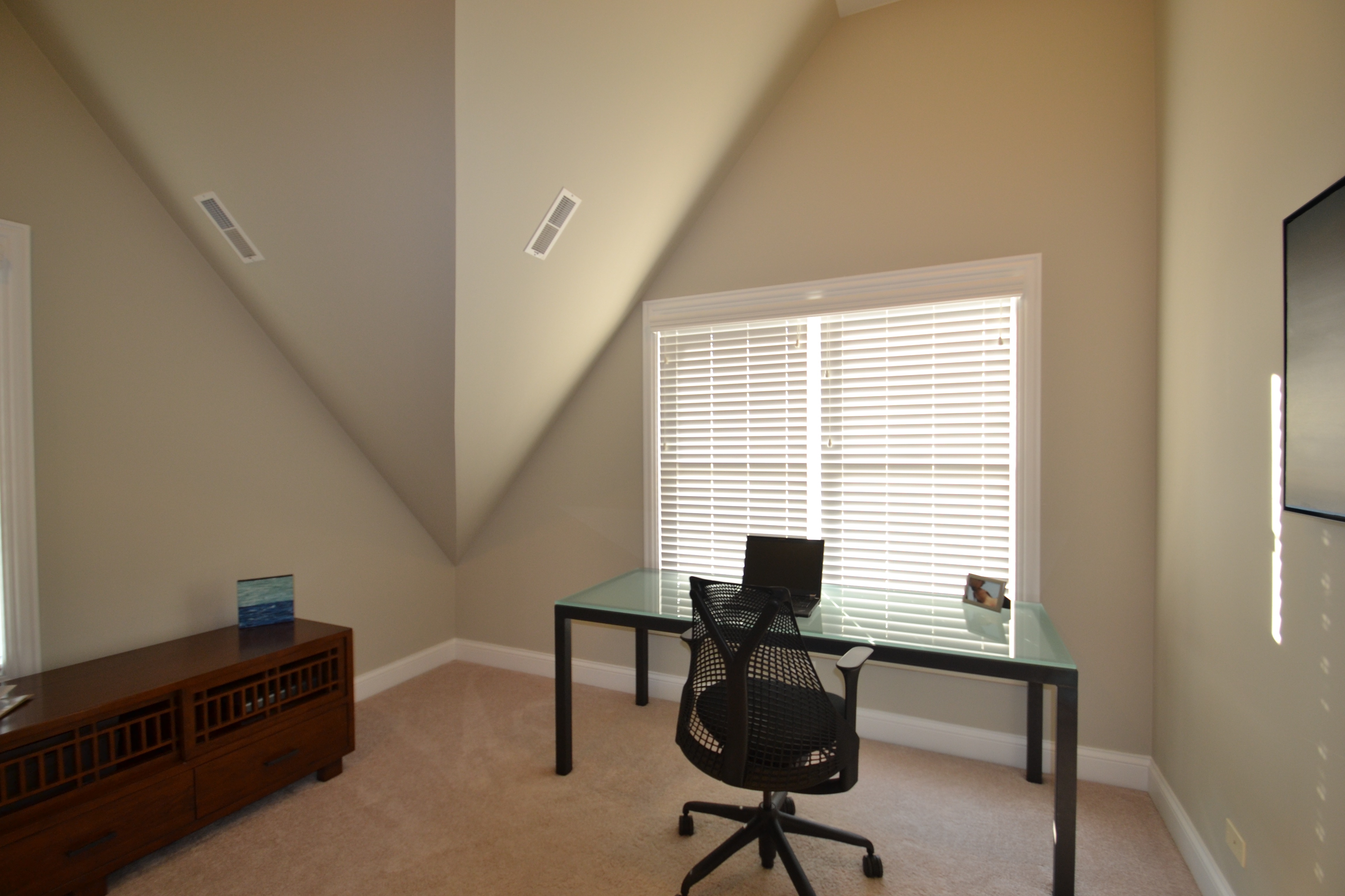 a desk in a room with a window and blinds