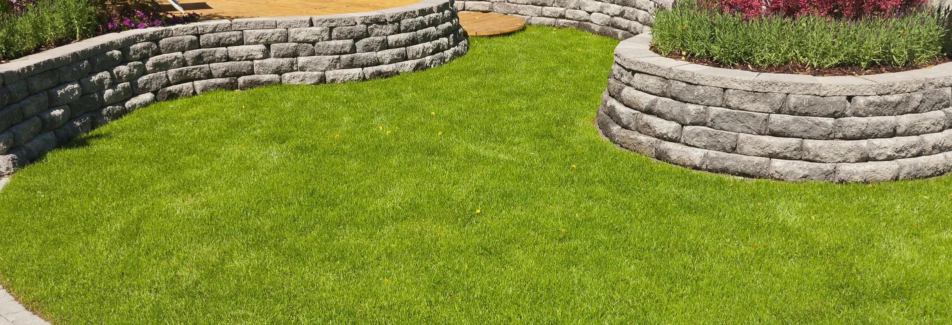 a grass field with a stone wall