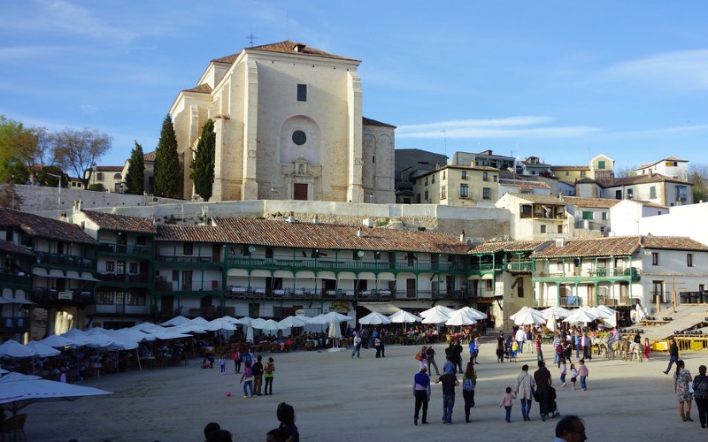 a group of people in a square with tents in front of a building