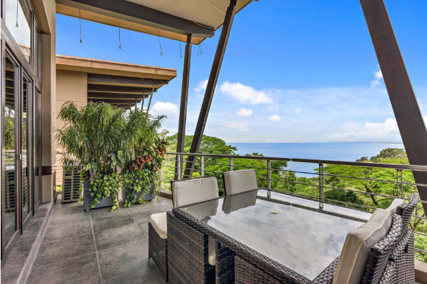 a table and chairs on a balcony overlooking the ocean