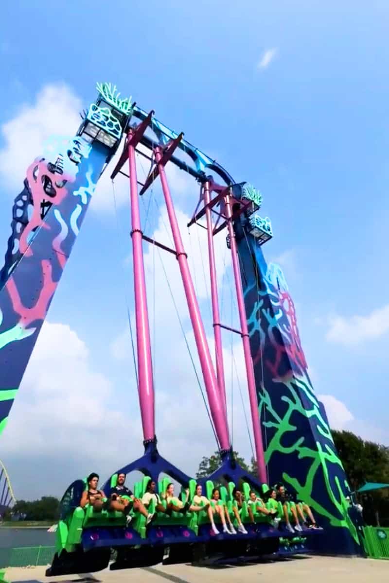 a group of people standing in front of a large colorful ride