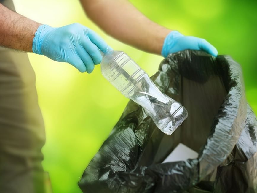 a person putting a plastic bottle into a trash bag