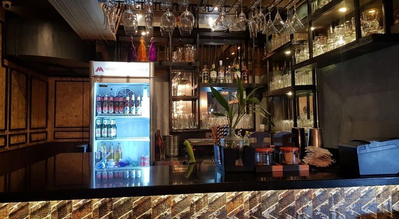 a bar with a fridge and wine glasses