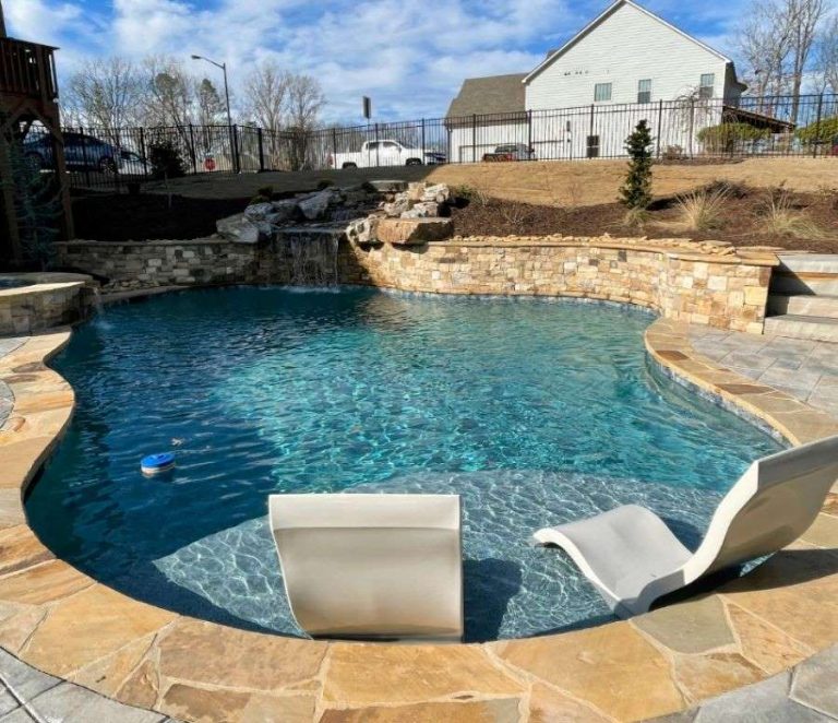 a pool with a waterfall and chairs