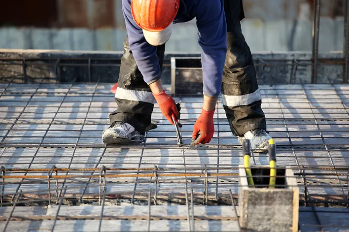 a man wearing a hard hat and gloves working on a construction site
