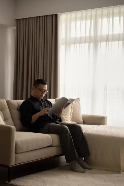 a man sitting on a couch reading a book