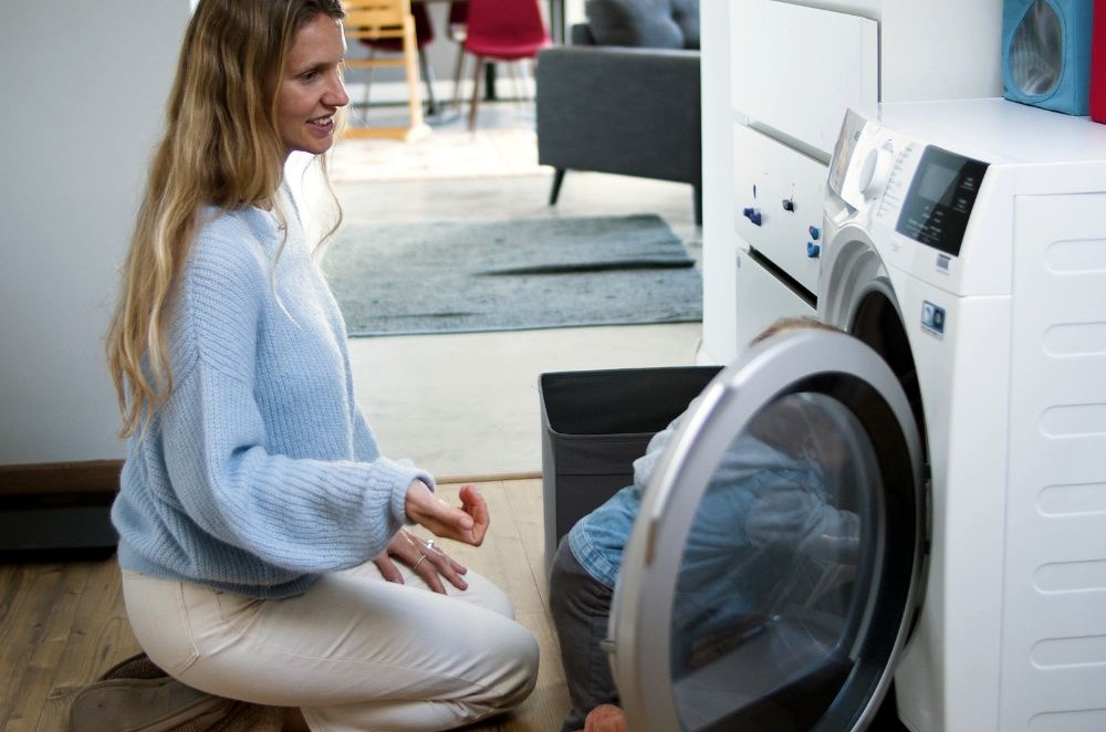 a woman and a child looking at a washing machine