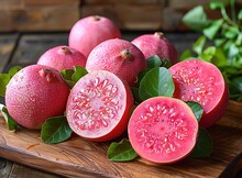 a group of pink fruit with leaves on a wooden surface