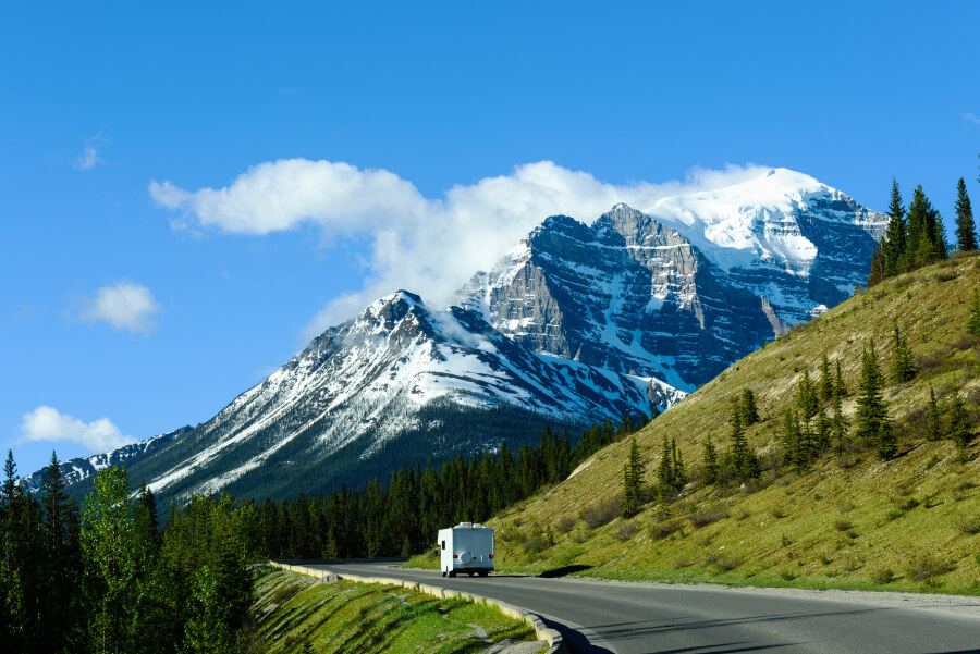 a road with a white rv on it and a mountain in the background