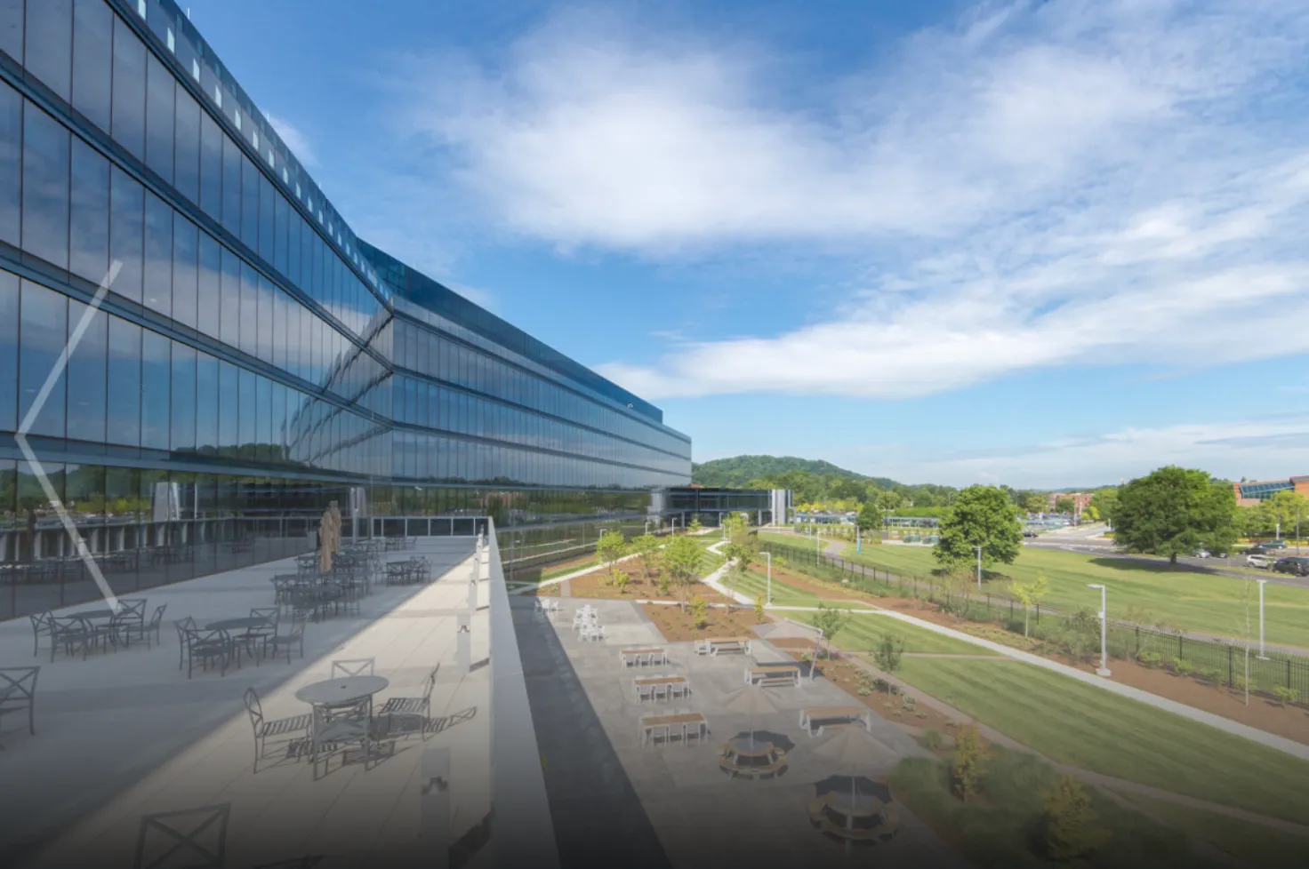 a building with glass walls and a lawn and a grassy field