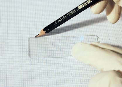 a hand holding a pencil and a rectangular piece of paper