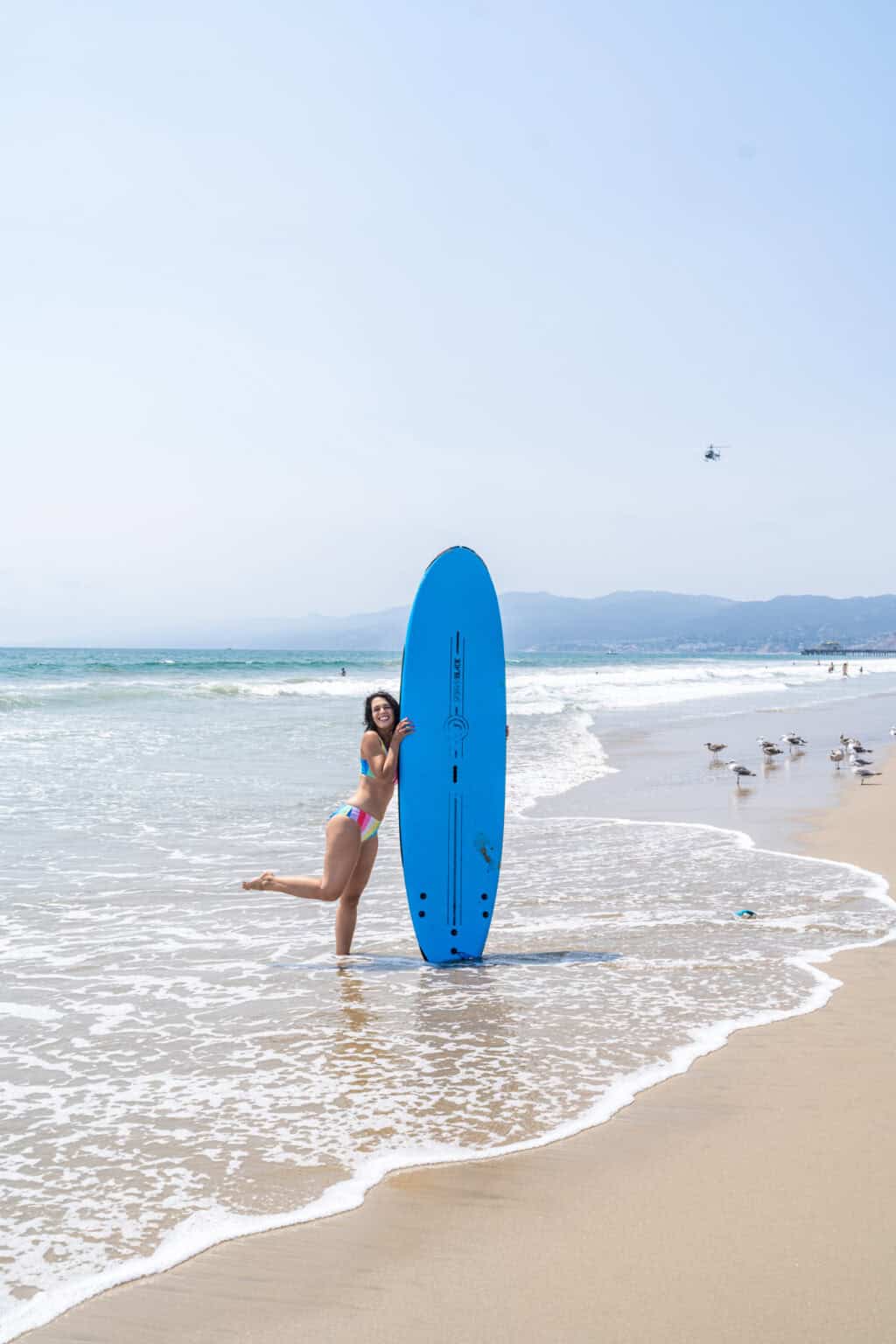 a woman in a garment holding a surfboard on a beach