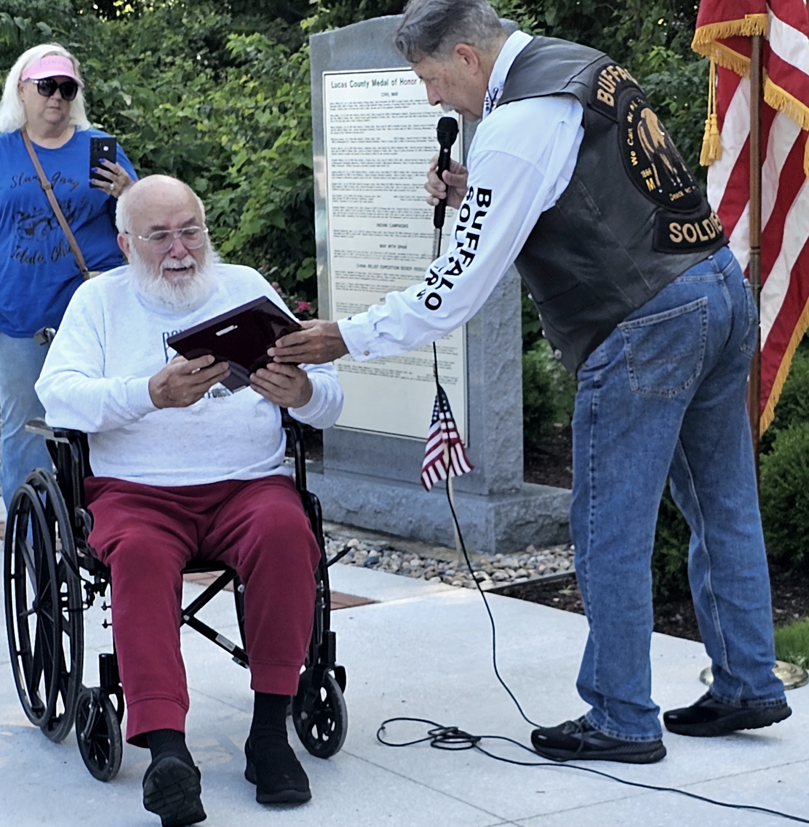 a man holding a book to a man in a wheelchair