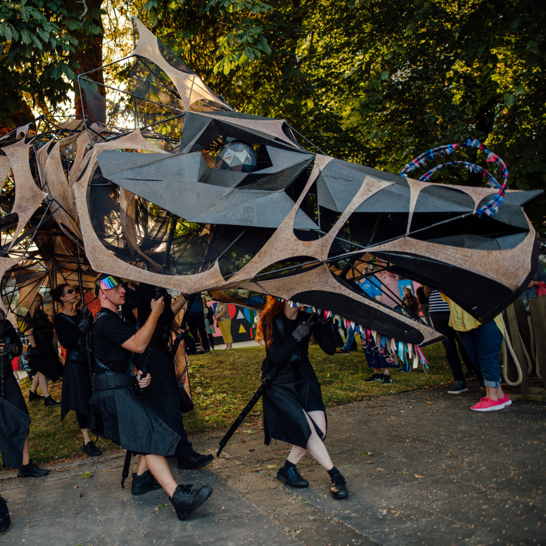 a group of people walking with a large sculpture