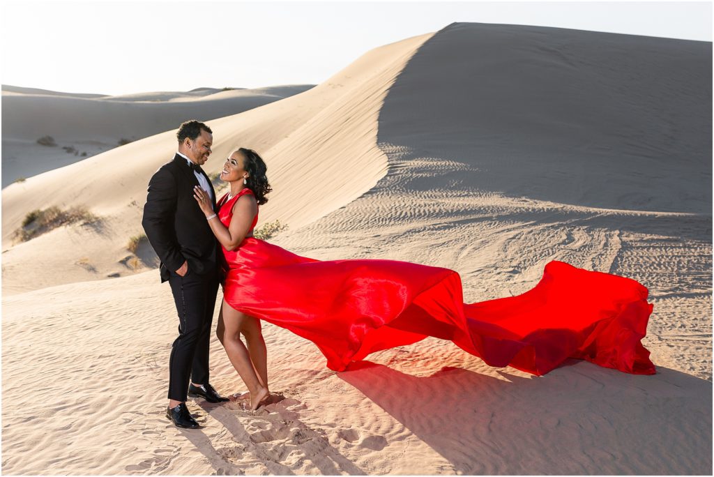 a man and woman in a red dress in the desert
