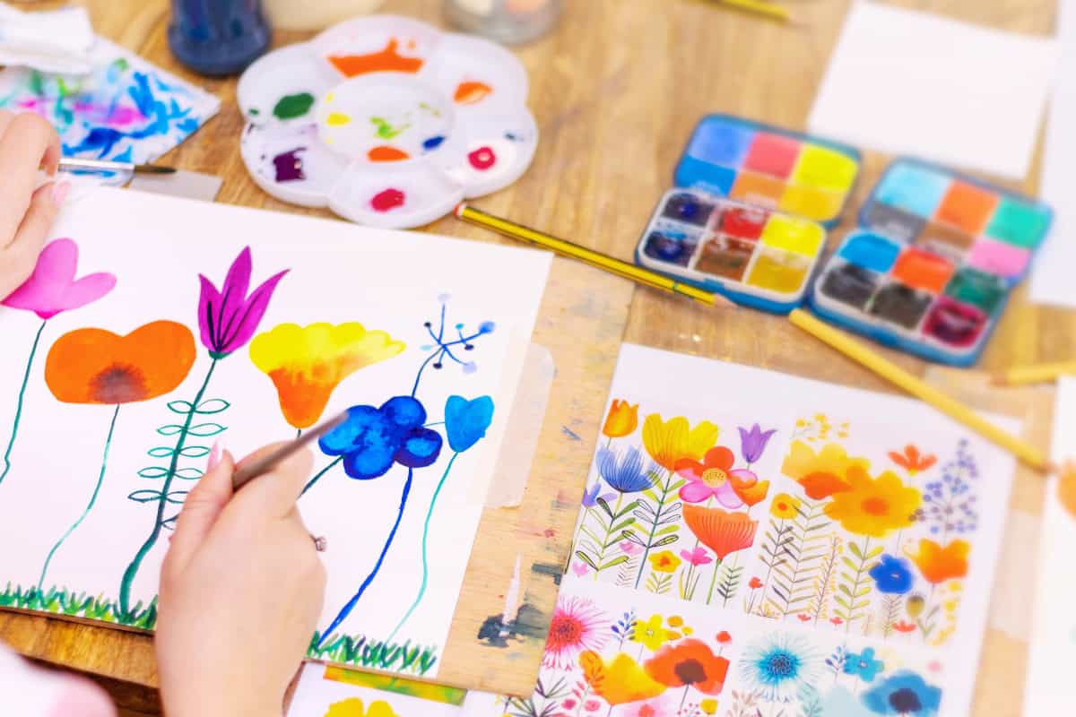 a person painting flowers on paper