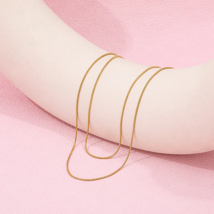 a person's arm with gold necklaces