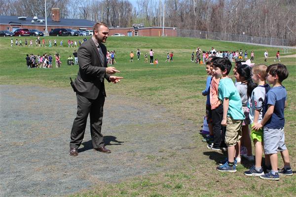 a man in a suit talking to a group of children