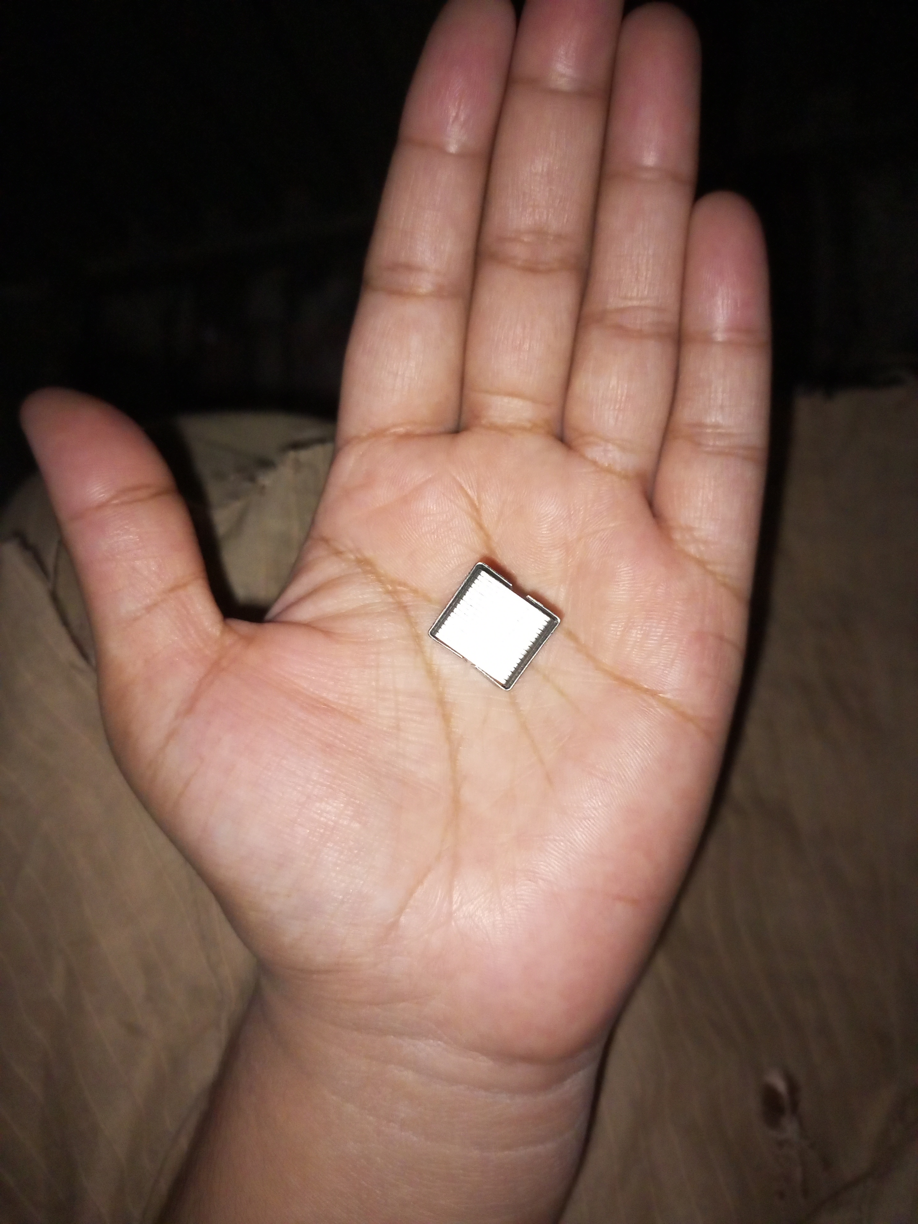 a hand holding a small square object