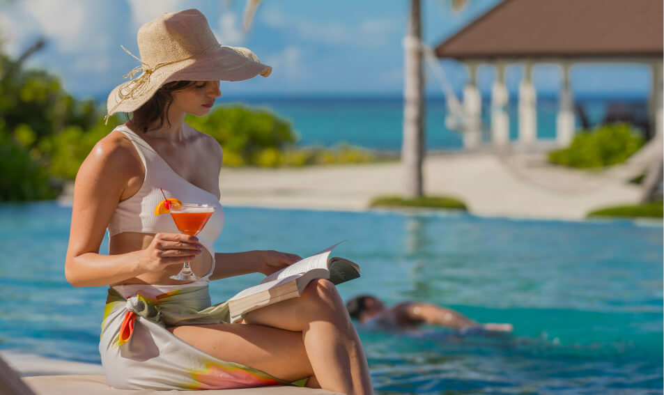 a woman sitting on a pool edge reading a book