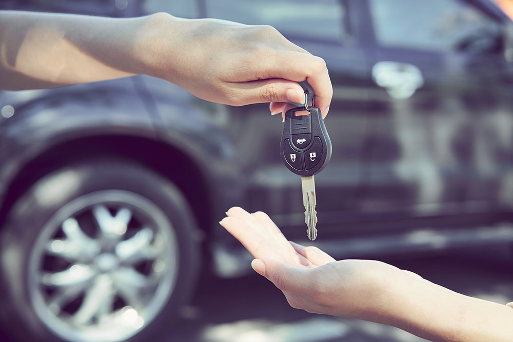 a person handing over a car key