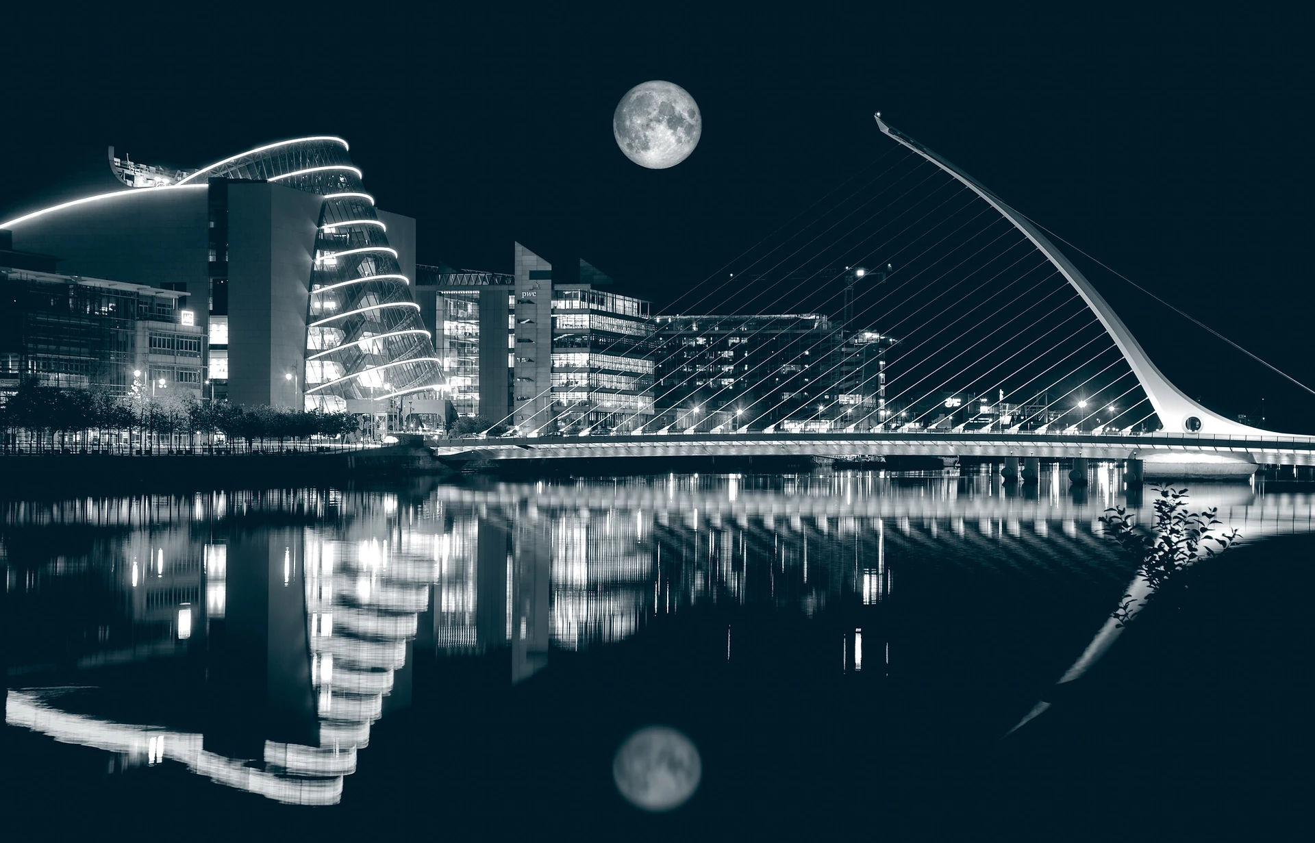 a bridge over water with a city and the moon