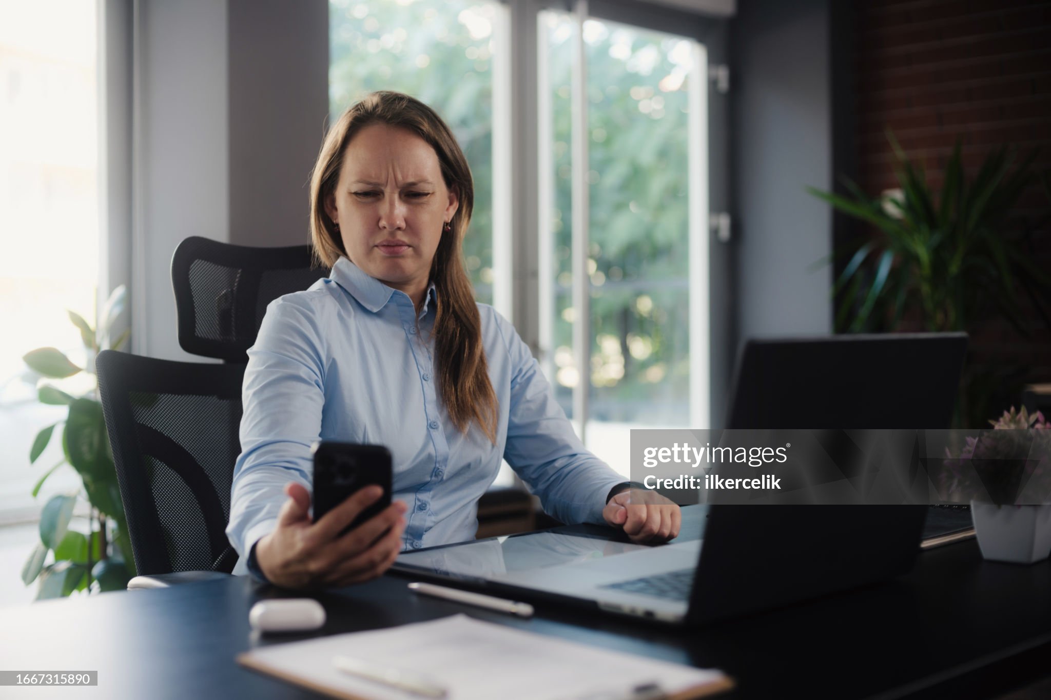 a woman sitting at a desk looking at a phone