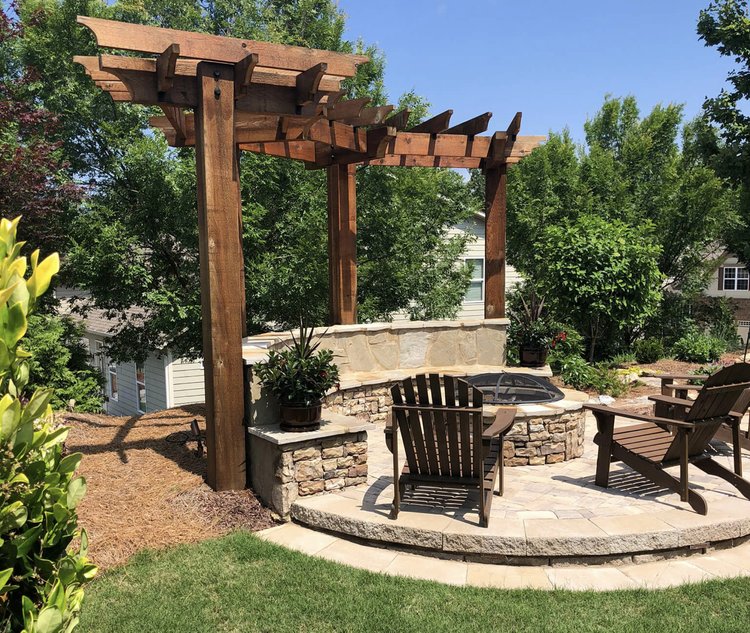 a patio with a wood structure and a fire pit