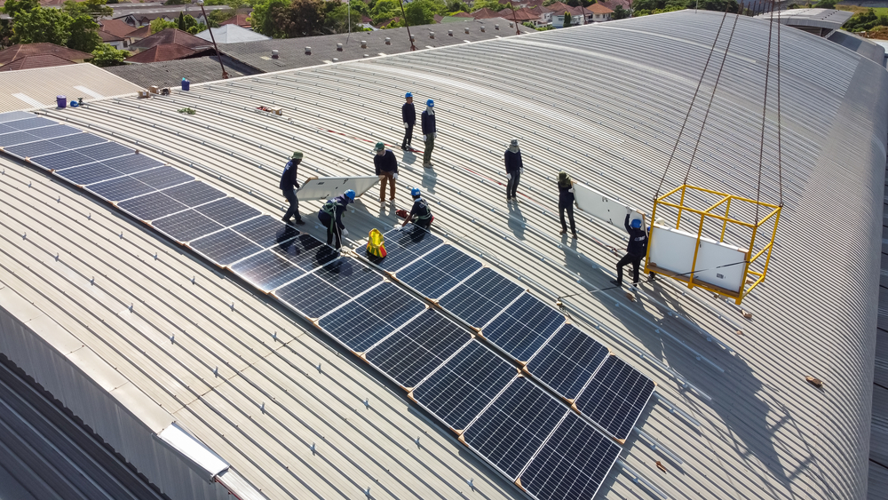 a group of people standing on a roof with solar panels